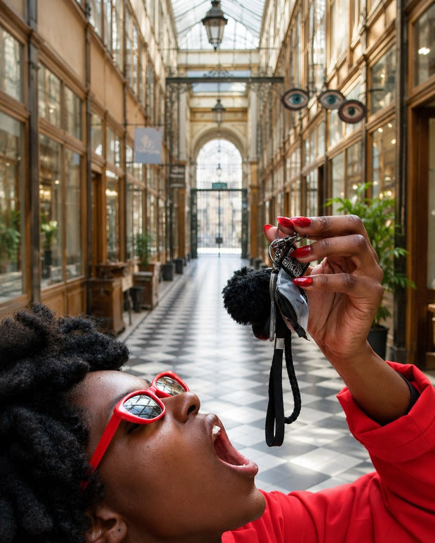 Une femme tient son porte-clé My Self Key à bout de bras dans une galerie parisienne.
